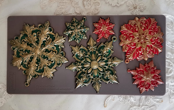 Decorative snowflake-shaped molds on a gray mat with a floral patterned background.