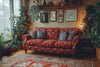 Living room with a floral-patterned red sofa, Christmas tree, and framed pictures on a wall.