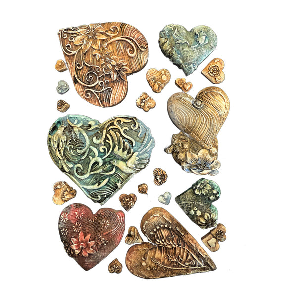 Collection of decorative heart-shaped castings with intricate designs on a white background