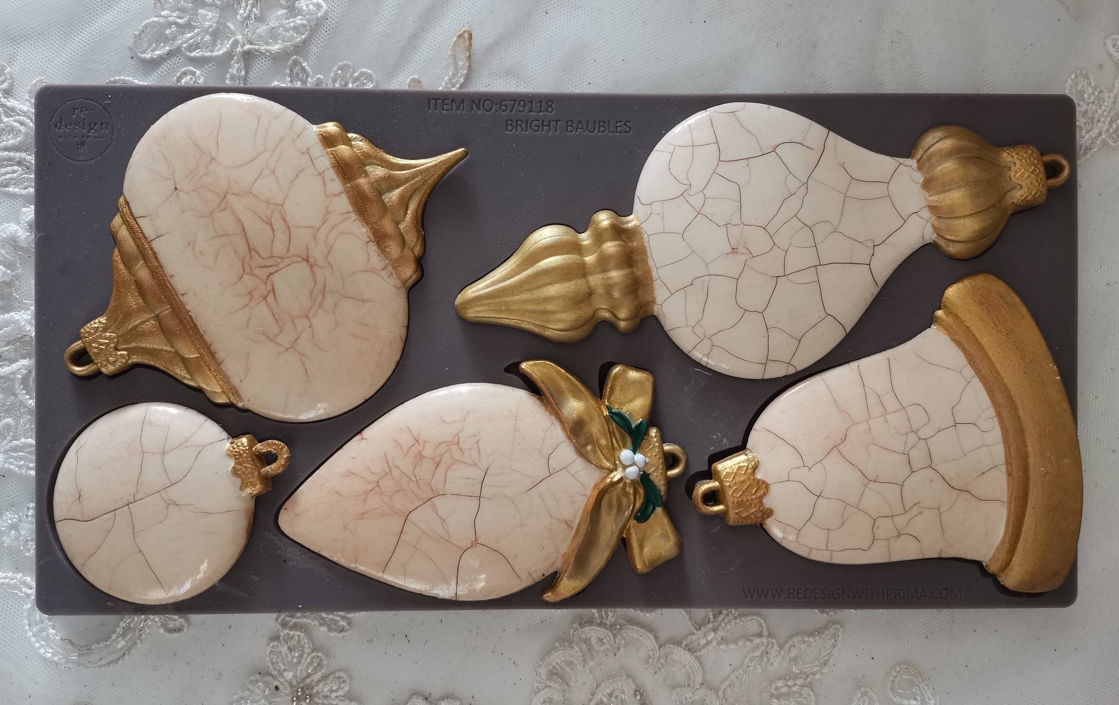 Decorative items with cracked surface and gold accents on a gray mat.