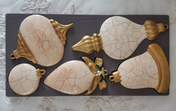 Decorative items with cracked surface and gold accents on a gray mat.