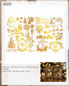 A package of 'fe design' Middy Foil Transfers holiday-themed foil sheets, featuring gold metallic designs of Santa Claus, Christmas trees, snowflakes, and 'Merry Christmas' text on white sheets, with a small photo of two framed holiday portraits at the bottom right.