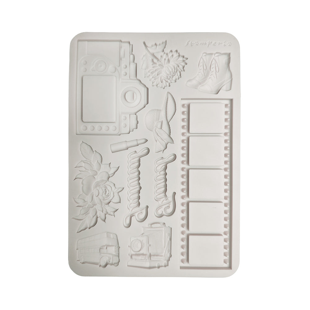 A rectangular white silicone mold with embossed travel-themed designs including a camera, flowers, boots, film reels, and a bus, shown on a plain white background.