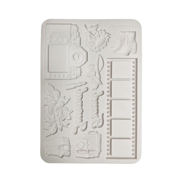 A rectangular white silicone mold with embossed travel-themed designs including a camera, flowers, boots, film reels, and a bus, shown on a plain white background.