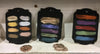 Three black wax swatches with colorful shades on a white surface.