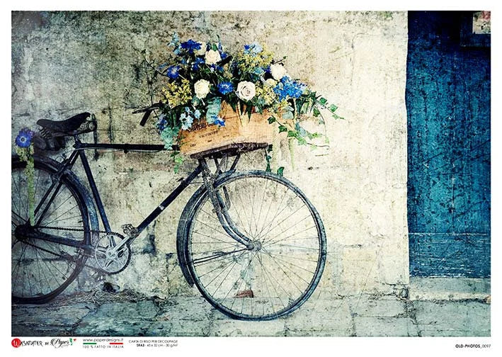 Vintage bicycle with a basket of flowers against a textured wall.