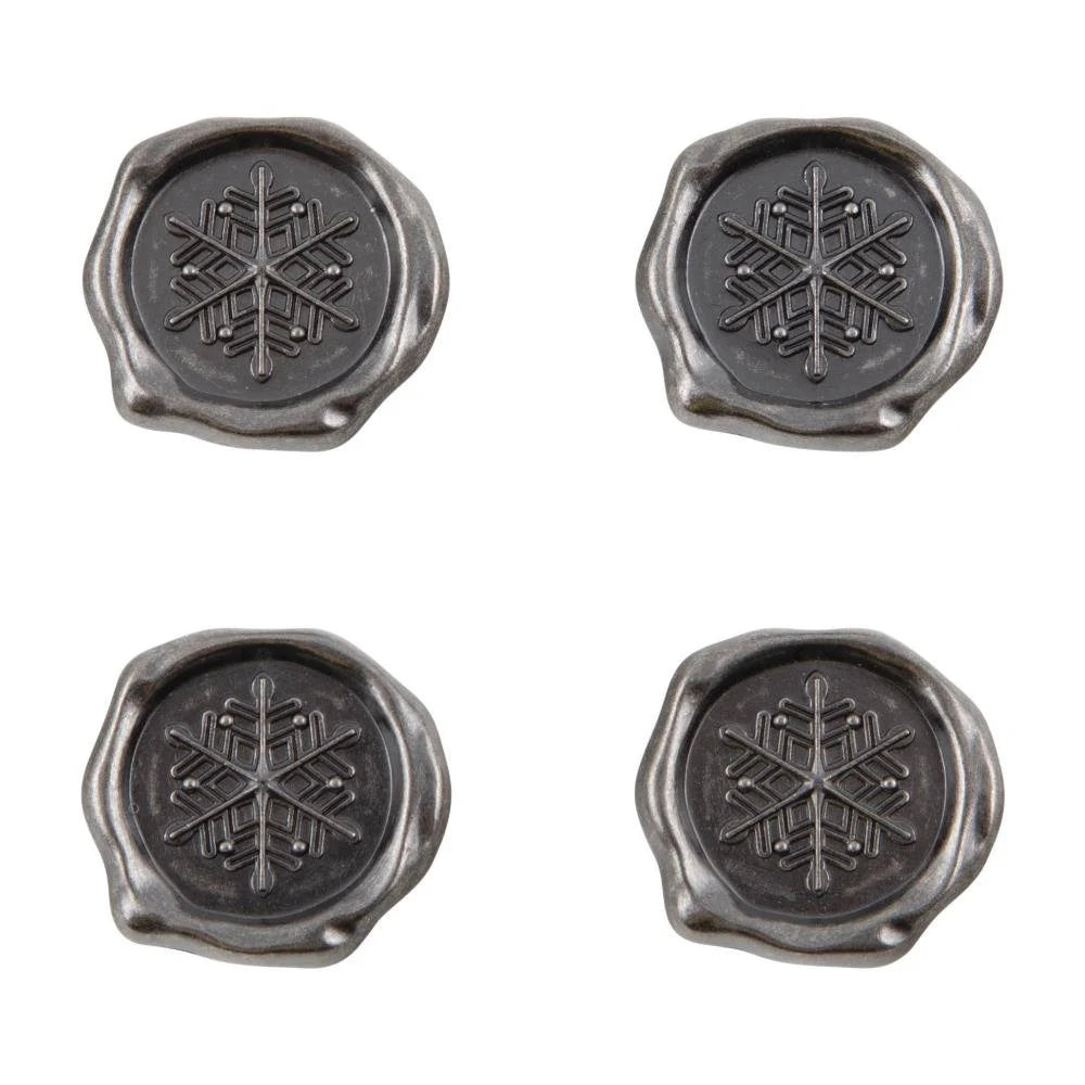 Four metallic seals with snowflake designs on a white background